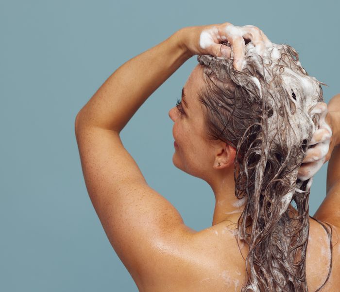 Woman with long hair washing with shampoo lather